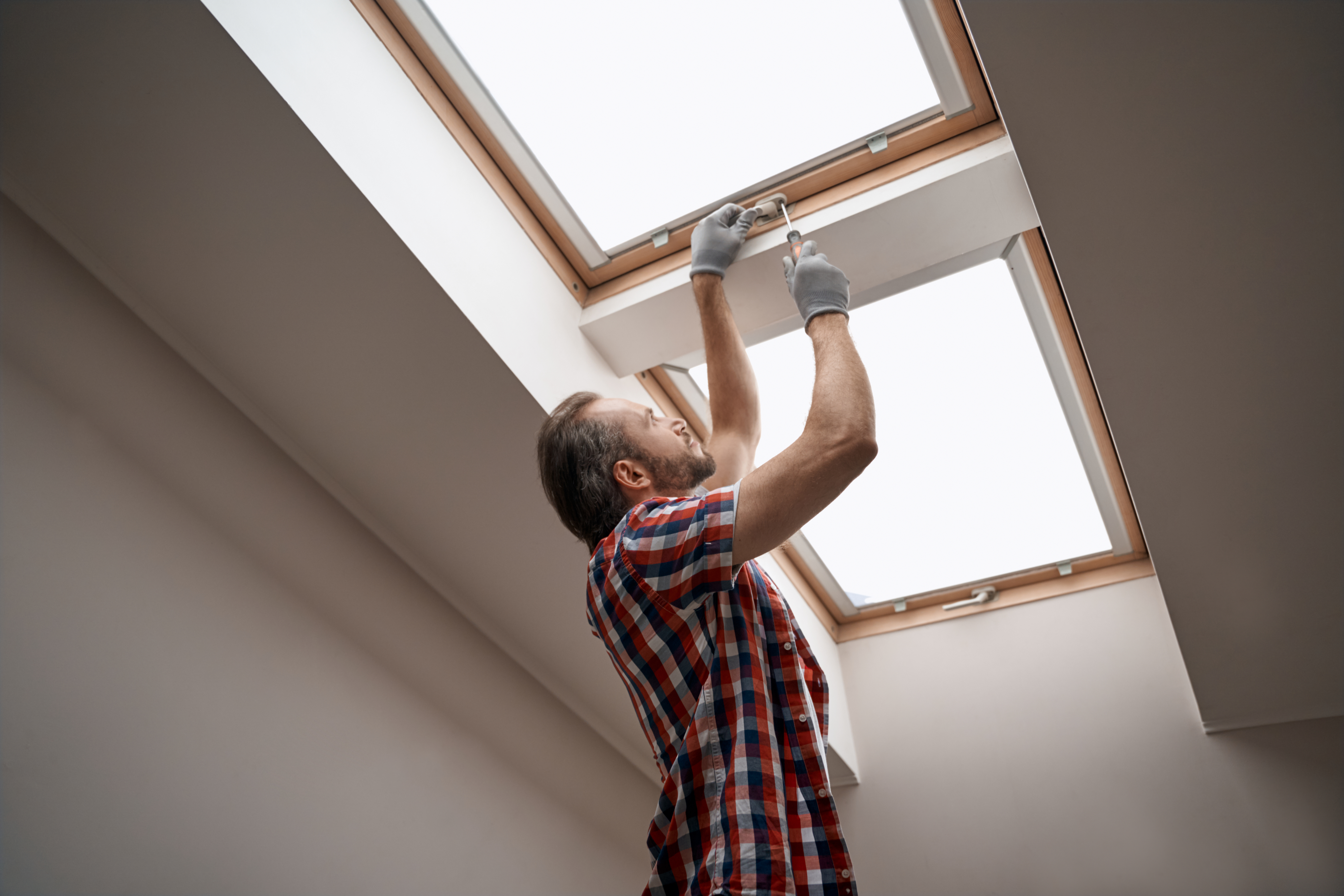 a contractor fixes the hinges on a skylight